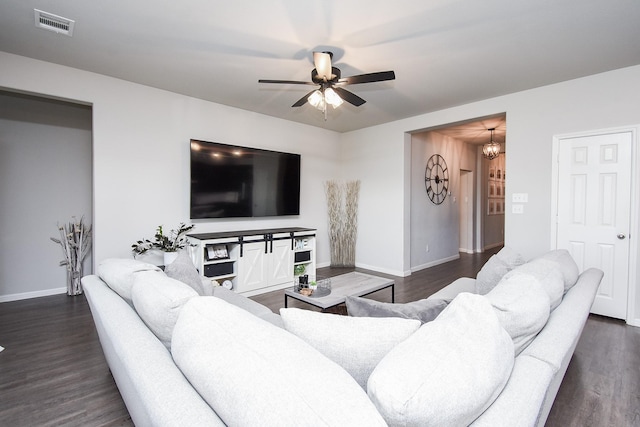 living room with dark hardwood / wood-style flooring and ceiling fan with notable chandelier