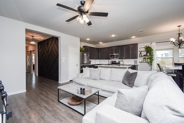 living room featuring ceiling fan with notable chandelier and wood-type flooring