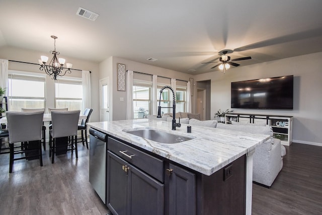 kitchen featuring decorative light fixtures, stainless steel dishwasher, sink, an island with sink, and light stone counters