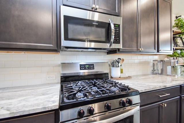 kitchen featuring stainless steel appliances, decorative backsplash, and dark brown cabinets