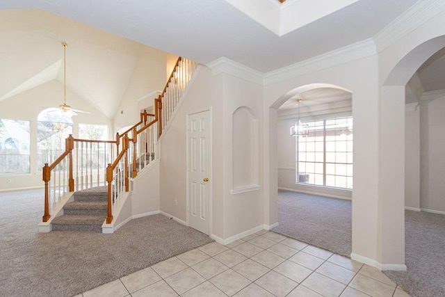 carpeted foyer entrance featuring crown molding, ceiling fan with notable chandelier, and lofted ceiling