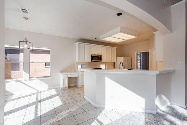 kitchen with kitchen peninsula, white fridge with ice dispenser, white cabinets, and a healthy amount of sunlight