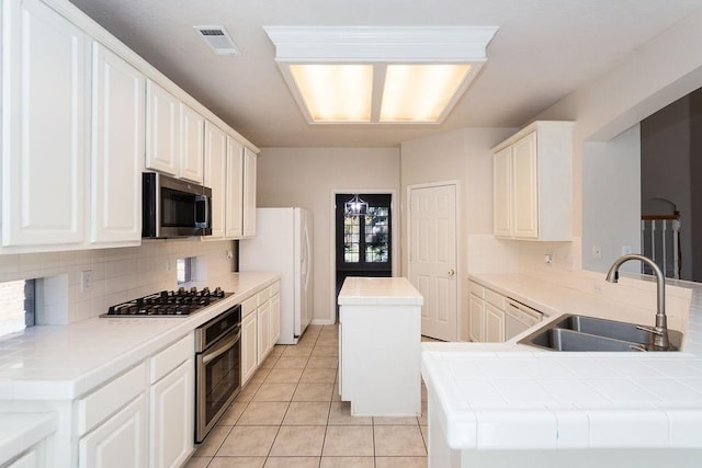 kitchen featuring tile counters, white cabinetry, sink, kitchen peninsula, and stainless steel appliances