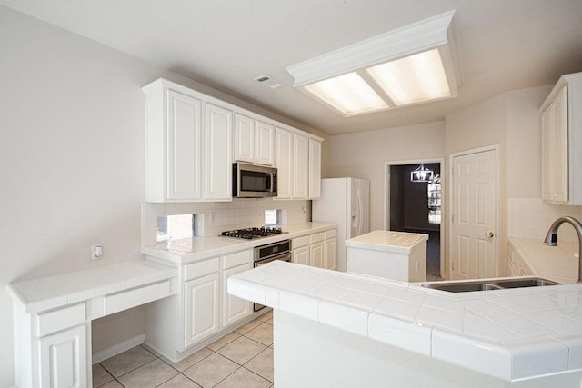 kitchen featuring white cabinetry, appliances with stainless steel finishes, kitchen peninsula, and tile countertops