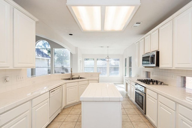 kitchen featuring white cabinets, a kitchen island, stainless steel appliances, sink, and light tile patterned floors