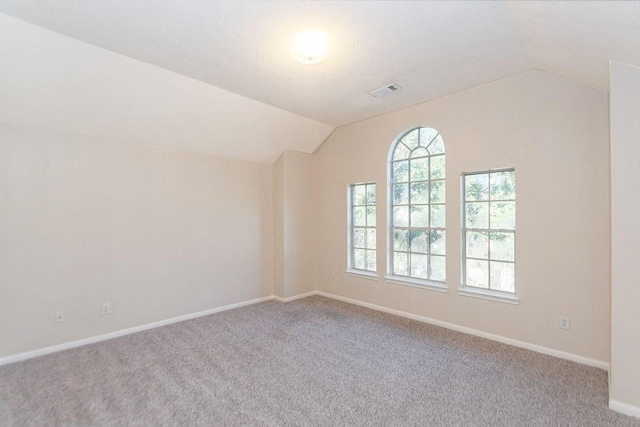 carpeted spare room with lofted ceiling