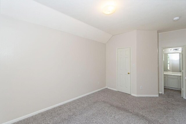 unfurnished bedroom with vaulted ceiling and carpet flooring