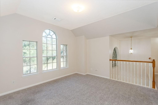 carpeted empty room with vaulted ceiling