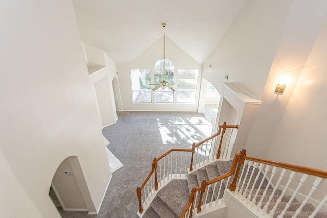 staircase with ceiling fan, high vaulted ceiling, and carpet