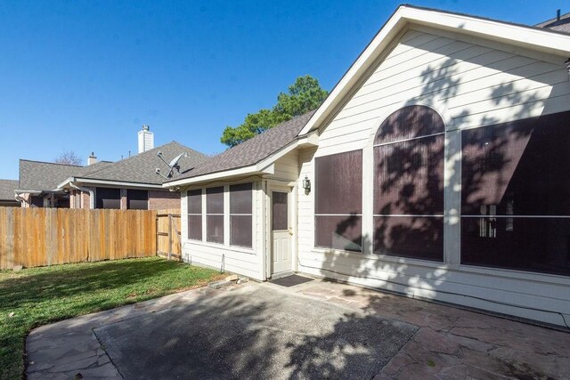 back of property featuring a yard, a sunroom, and a patio