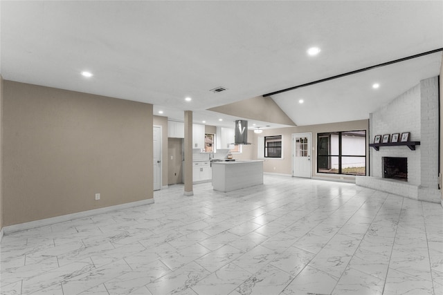 unfurnished living room with vaulted ceiling and a brick fireplace