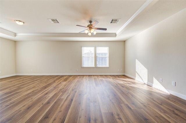 unfurnished room with ceiling fan, dark wood-type flooring, a tray ceiling, and ornamental molding