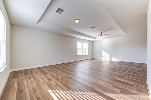 spare room featuring a raised ceiling, ceiling fan, and hardwood / wood-style flooring