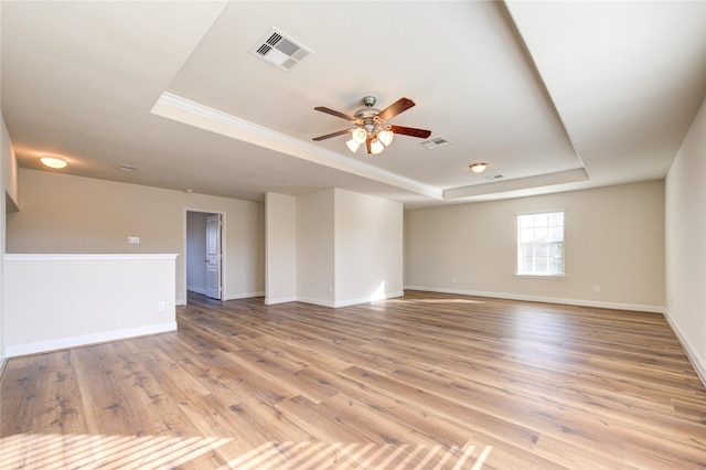 spare room featuring ceiling fan, a tray ceiling, and light wood-type flooring