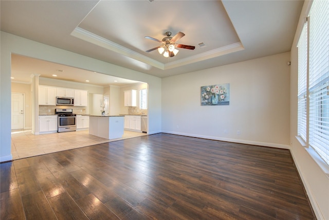 unfurnished living room with ceiling fan, hardwood / wood-style floors, crown molding, and a raised ceiling