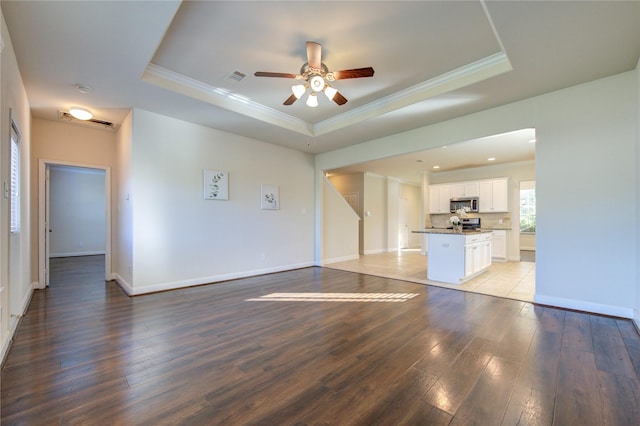 unfurnished living room with ceiling fan, light hardwood / wood-style floors, and a raised ceiling