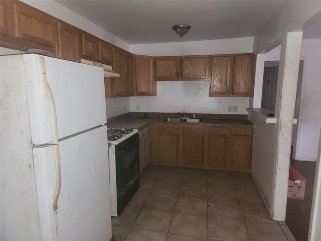 kitchen with sink, range with gas cooktop, light tile patterned flooring, and white refrigerator