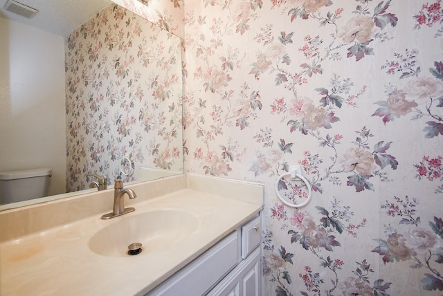 bathroom featuring a textured ceiling, toilet, and vanity