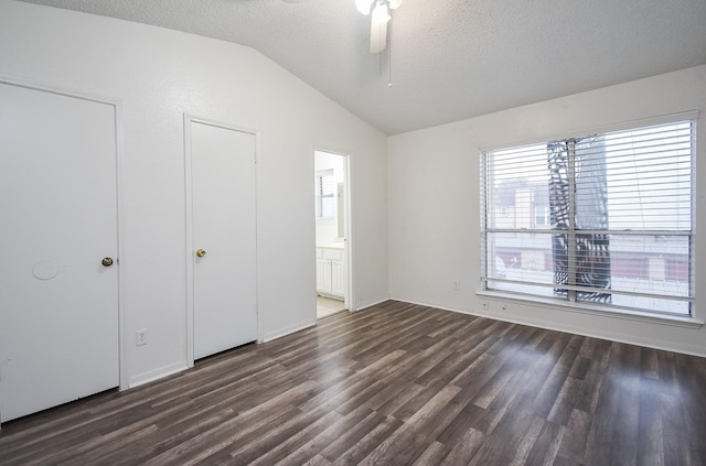 unfurnished bedroom with ensuite bathroom, ceiling fan, dark hardwood / wood-style flooring, lofted ceiling, and a textured ceiling