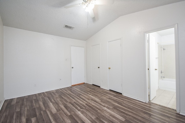 unfurnished bedroom featuring ensuite bathroom, ceiling fan, dark hardwood / wood-style floors, lofted ceiling, and a textured ceiling