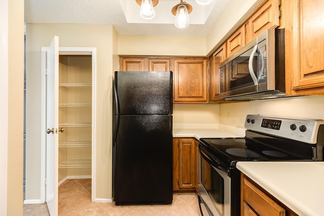 kitchen featuring a textured ceiling, light tile patterned floors, and appliances with stainless steel finishes