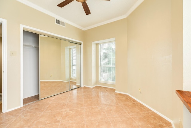 unfurnished bedroom with light tile patterned floors, ceiling fan, ornamental molding, and a closet