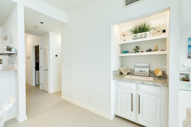 bar featuring white cabinets and light stone counters