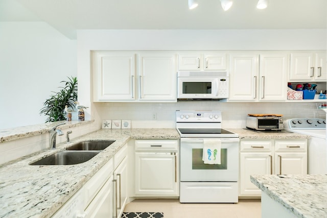 kitchen featuring white appliances, washer / clothes dryer, light stone countertops, white cabinetry, and sink