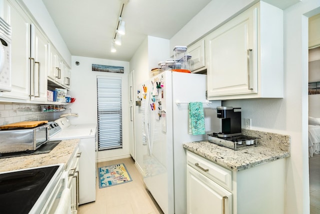 kitchen featuring washing machine and dryer, white cabinetry, white appliances, and light stone counters