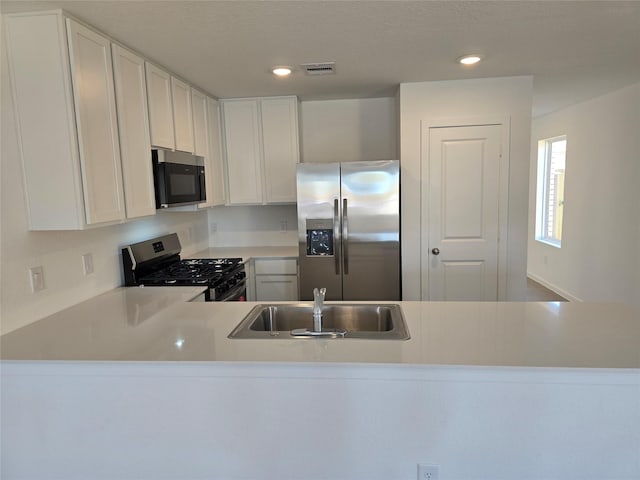 kitchen with white cabinets, kitchen peninsula, sink, and stainless steel appliances