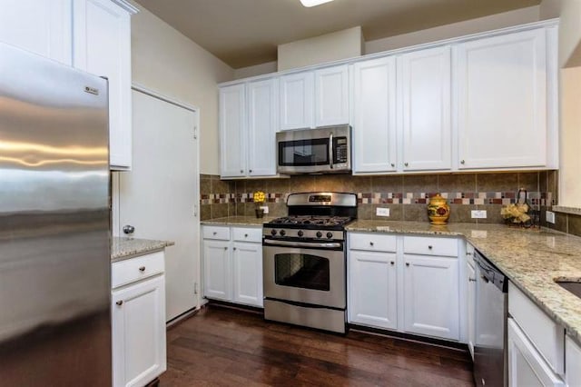 kitchen with dark hardwood / wood-style floors, decorative backsplash, white cabinetry, stainless steel appliances, and light stone counters