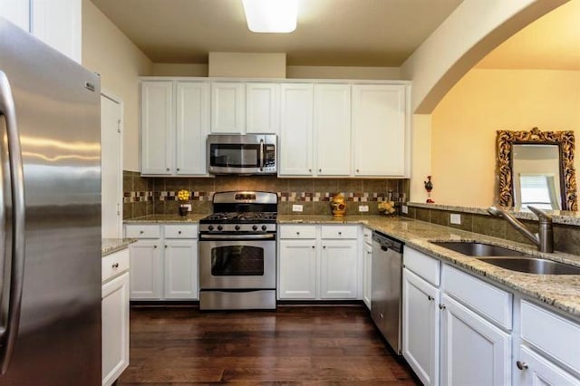 kitchen with light stone countertops, white cabinets, appliances with stainless steel finishes, and sink