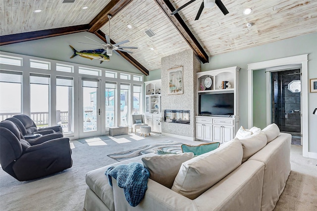 carpeted living room with ceiling fan, wood ceiling, beam ceiling, and a stone fireplace