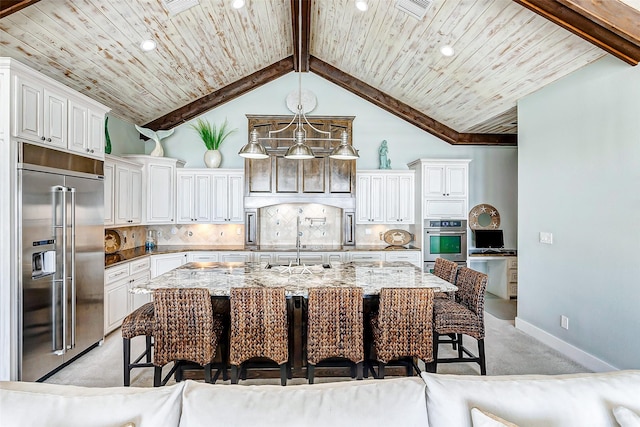 kitchen featuring tasteful backsplash, a kitchen island with sink, appliances with stainless steel finishes, and light stone countertops