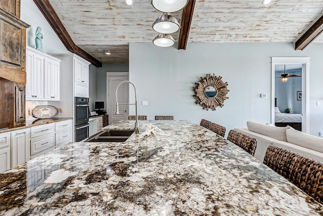 kitchen featuring sink, white cabinets, a breakfast bar area, and wood ceiling