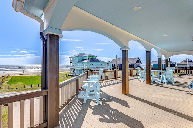 wooden terrace featuring a water view and a beach view