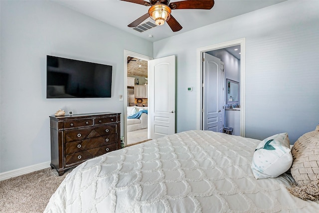 bedroom with ceiling fan, ensuite bath, and light carpet