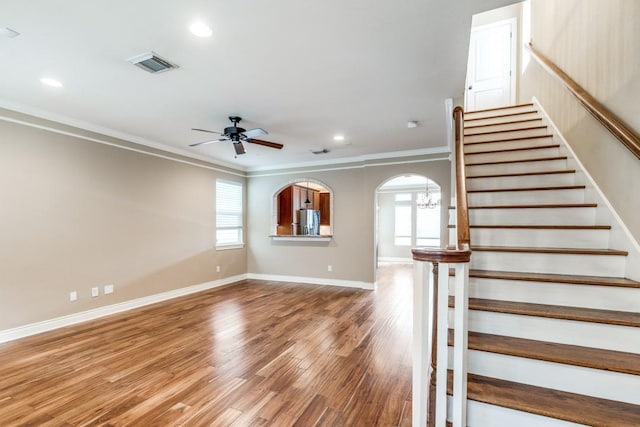 interior space with crown molding, a wealth of natural light, and ceiling fan with notable chandelier