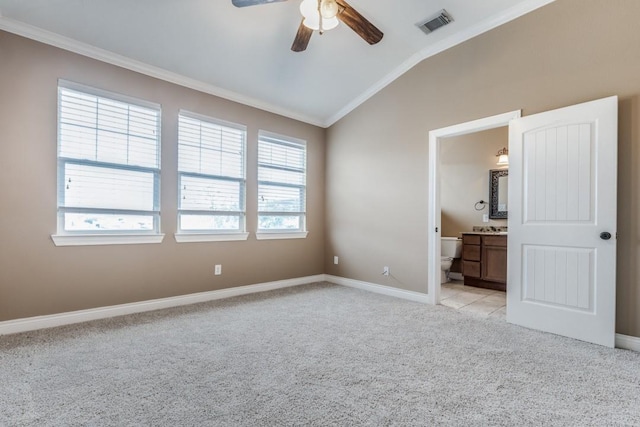 unfurnished bedroom featuring light carpet, ceiling fan, ensuite bath, vaulted ceiling, and crown molding