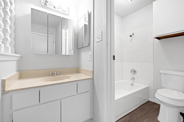 full bathroom with toilet, hardwood / wood-style flooring, tiled shower / bath, a textured ceiling, and vanity