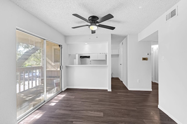 unfurnished living room with ceiling fan, a textured ceiling, and dark hardwood / wood-style flooring