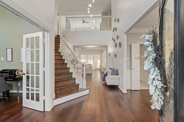 entryway featuring french doors, dark hardwood / wood-style floors, crown molding, and a towering ceiling