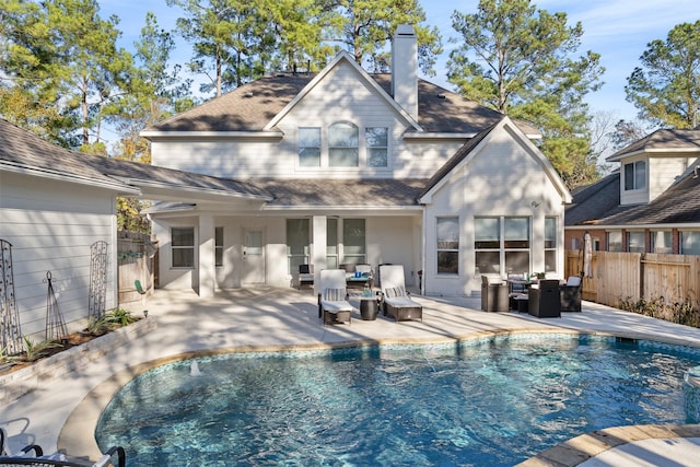 back of property featuring an outdoor living space, a patio area, and a fenced in pool