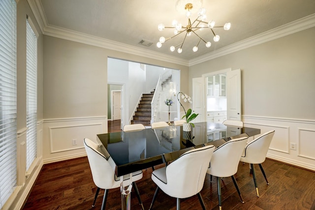 dining area with dark hardwood / wood-style floors, crown molding, and an inviting chandelier