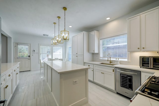 kitchen with white cabinetry, dishwashing machine, decorative light fixtures, a kitchen island, and sink