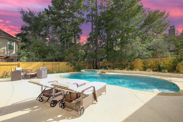 pool at dusk featuring a patio area, an in ground hot tub, and an outdoor living space