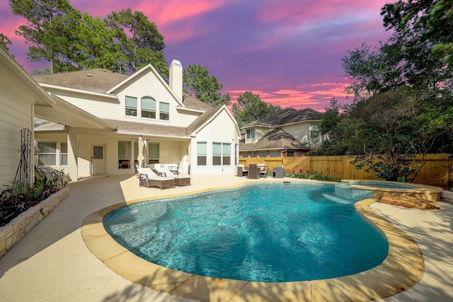 pool at dusk featuring an in ground hot tub, outdoor lounge area, and a patio area