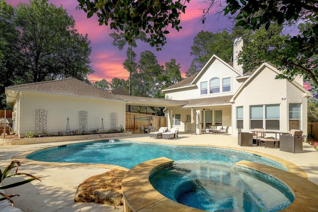 pool at dusk with an outdoor living space, a patio area, and an in ground hot tub