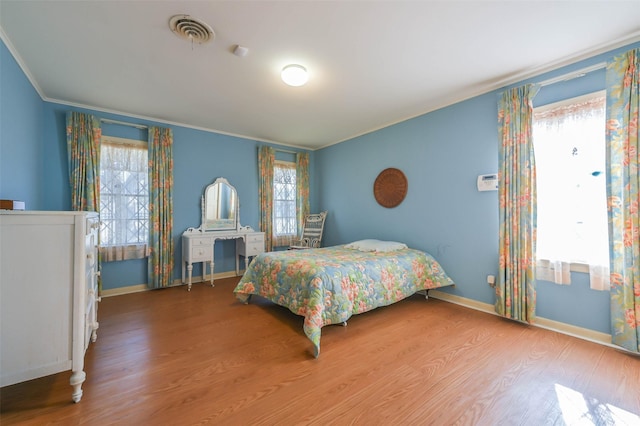 bedroom with crown molding, hardwood / wood-style flooring, and multiple windows