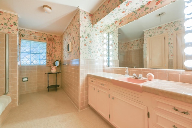 bathroom featuring an enclosed shower, vanity, and tile walls